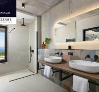 A bathroom in a villa with sinks, a large mirror, and a view of the sea.