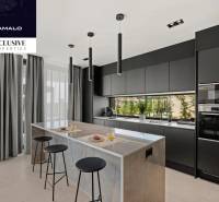 A kitchen in a villa with a stylish sharp design, a large island, and black cabinets.