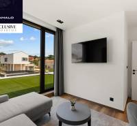 Living room in a villa with a large window, television, and wooden decor flooring.