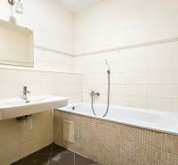 White bathroom with a sink and bathtub in a 2-room apartment.