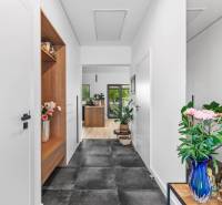 A hallway in a family house with plants, a mirror, wooden and white elements.
