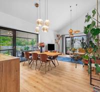 Interior of a family house with a dining room, living room, wooden decor, and large windows.