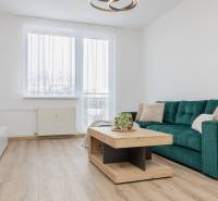 Living room in a two-room apartment with a wooden decor floor, green sofa, modern table.