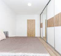 Bedroom with built-in wardrobe and bed, 2-room apartment, floor with wooden decor.