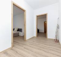 A hallway in a 2-room apartment with a wooden decor floor and two open doors.