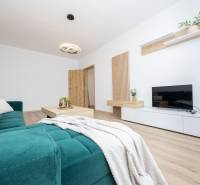 A spacious living room in a two-room apartment with a wooden decor floor and a comfortable sofa.