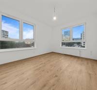 A room in a 3-room apartment with a large window and a floor with a wooden decor.