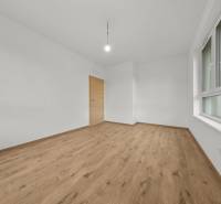 A room in a 3-room apartment with a wooden decor floor and white walls.