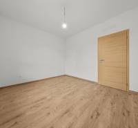 A room in a 3-room apartment with white walls and a wooden decor floor.