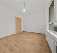 A spacious room with a wooden decor floor in a 3-room apartment.