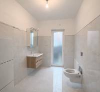 Bathroom in a family house with white tiles and a wall-mounted sink.
