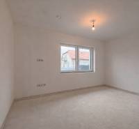 A spacious room in a family house with a window overlooking another house.