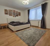 Bedroom in a family house with a bed, carpet, curtains, and a wooden decor floor.