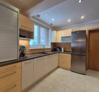 A kitchen in a family house with beige cabinets, white appliances, and orange tiles.
