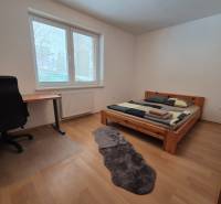 Bedroom with a bed and a desk, wooden decor flooring in a family house.