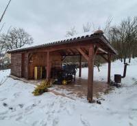 A snowy plot of land with a wooden shelter next to a family house in Myjava.