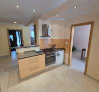 A kitchen in a family house with built-in appliances and light tiles on the floor.