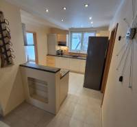 A kitchen in a family house with white cabinets, lighting, and modern appliances.