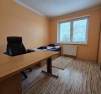 A room in a family house with a bed, table, chair, and a floor with a wooden decor.