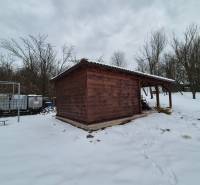 A snow-covered garden with a wooden cottage near a family house in Myjava.