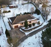A winter scenery of a family house in Myjava surrounded by a snowy landscape and trees.