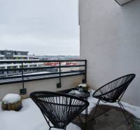 Snow-covered balcony with chairs and a view of Strojárenská Street in Košice, Old Town.