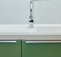 A kitchen cabinet with green doors and a chrome faucet in a 2-room apartment.