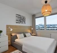 Bedroom in a two-room apartment with a bed, dresser, and floor with wood decor.