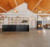 The interior of a building with a floor, minimalist furniture, a fireplace, and large windows.