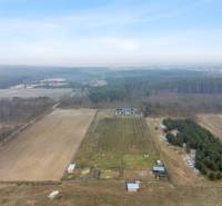 In the rural area of Láb, there is a farm building surrounded by fields and forest.