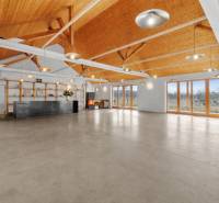 A spacious interior of a building with a high wooden ceiling and a concrete floor.