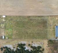 Aerial view of agricultural land with a building on the edge in the village of Láb.