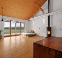 Interior of a building with a fireplace, large windows, and a wooden decor floor.