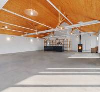 A space in a building with a wooden ceiling, large windows, and a reception desk.