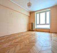 A bright room in a 2-room apartment with a wood-patterned floor and a large window.