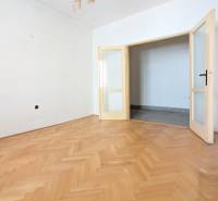 An empty room with white walls and a wooden decor floor in a two-room apartment.