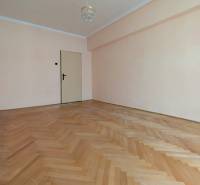 A spacious room with a wooden decor floor in a 2-room apartment.