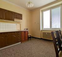 A kitchen with a brown cabinet and a table in a two-room apartment, colorful carpet.