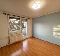 A room with a wooden decor floor and a balcony in a 3-room apartment.