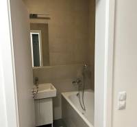 Bathroom in a 2-room apartment with a bathtub, sink, and tiles.