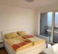 A bedroom in a 2-room apartment with light furniture and a wooden decor floor.