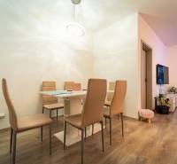 Dining area with a table and six chairs, wooden decor flooring in a 2-room apartment.