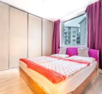 Bedroom in a 2-room apartment with wood-patterned flooring, a bed, and wardrobes.