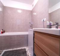 Bathroom with tiles and a bathtub in a 2-room apartment.