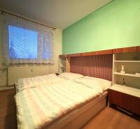 A two-room apartment with light walls, a large window, and a floor with a wooden decor.