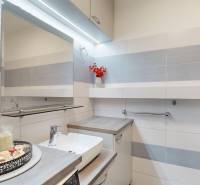 Bathroom in a 3-room apartment with white tiles and elegant decoration on the shelf.