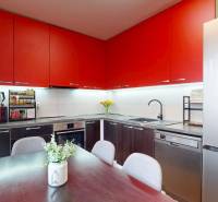 A kitchen with red cabinets and a wood-patterned floor in a three-room apartment.