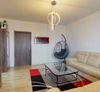 Living room in a 3-room apartment, white sofa, rocking chair, floor with wooden decor.
