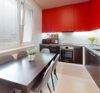 A kitchen in a 3-room apartment with red cabinets and a dining table.