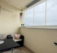 Glazed loggia in a 3-room apartment with comfortable seating and decorations.